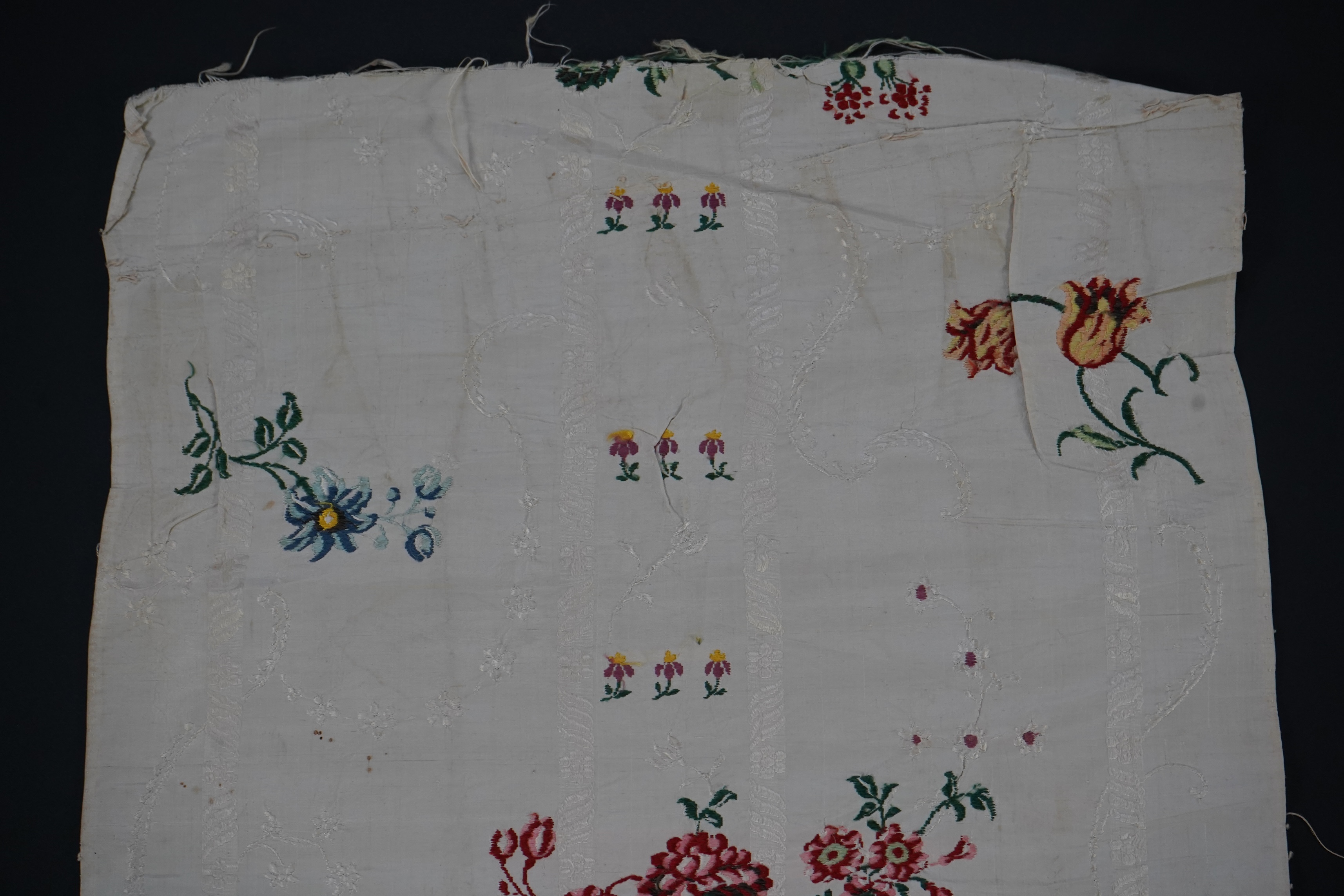 A length of 18th century short loom hand woven Spitalfields silk dress fabric, woven in cream silk with all over multicoloured spot floral motifs in a large repeat. 82cm repeat, total length of fabric 100cm x 48.5cm wide